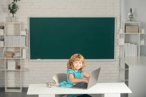 Divertente ragazzo sorridente scuola che studia al computer a scuola. Piccolo studente che usa il pc moderno in classe. — Foto Stock