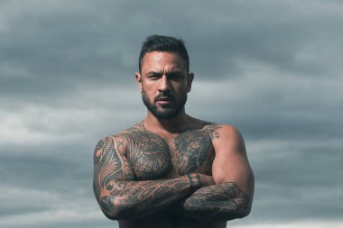 Yakışıklı bir adamın portresi. Güçlü kaslı erkek vücudu, kaslı adam. Dramatik gökyüzünde açık hava erkek portresi.