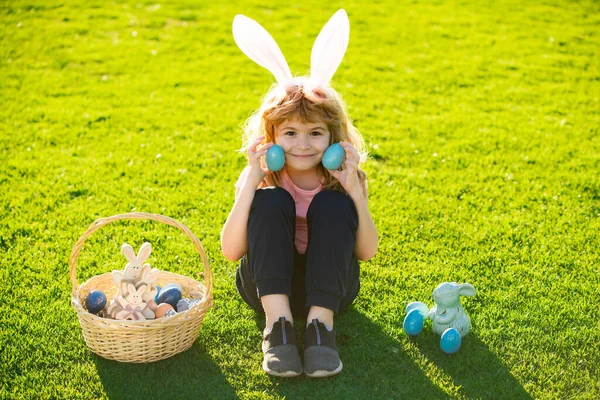 Paashaas kinderen. Kleine jongen in konijnenoren die eieren schildert. Grappige jongen, paashaas kinderen. — Stockfoto