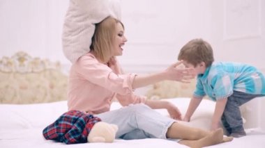 Sevgi dolu aile. Anne yatak odasında çocuk kucaklamasıyla oynuyor. Anne ve oğul evdeki yatakta birlikte oynuyorlar. Anneler Günü.