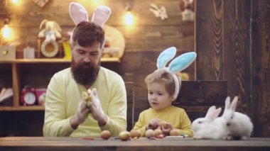Happy father and child son painted Easter eggs, wearing bunny ears on Easter day. Family leisure time.