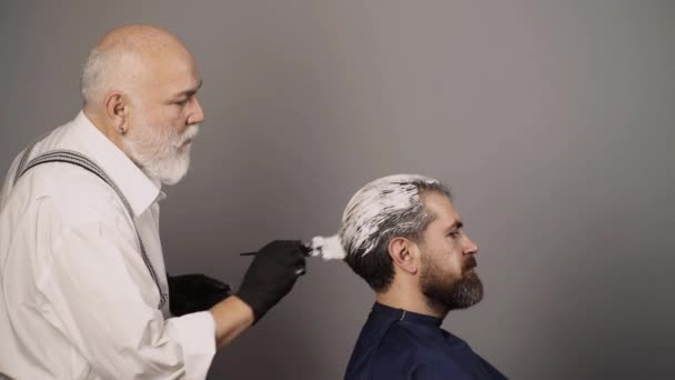 Coloriage homme processus capillaire. Salon de coiffure, coloriage homme. Beau coiffeur senior faisant une coupe de cheveux et une couleur de cheveux pour le client au salon de coiffure. — Video
