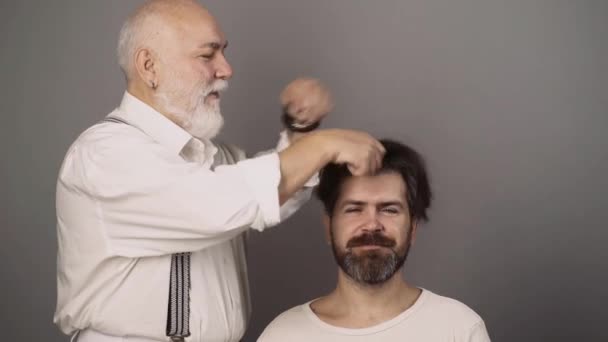 Homme barbu, salon de coiffure. Coiffeur professionnel peigne les cheveux de l'homme barbu dans le salon de coiffure. Barbier faire coupe de cheveux à l'homme attrayant dans le salon de coiffure. — Video
