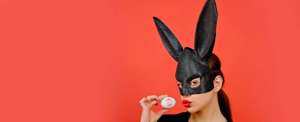 Easter banner with bunny woman. Woman rabbit, easter bunny girl. Red lip imprint on easter egg on red background. Female mouth kiss. Print of red lips on white egg. — Fotografia de Stock