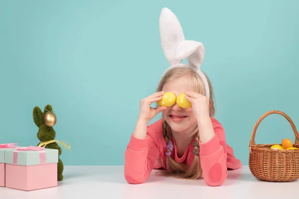 Lindo niño pequeño con orejas de conejo en el día de Pascua. Chica sosteniendo huevos pintados en los ojos. Semana Santa niños vacaciones. —  Fotos de Stock