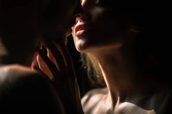 Sensual couple in the tender passion. Close up portrait of woman embracing and going to kiss man. Loving couple kissing over black background. Sexy lips. — Fotografia de Stock
