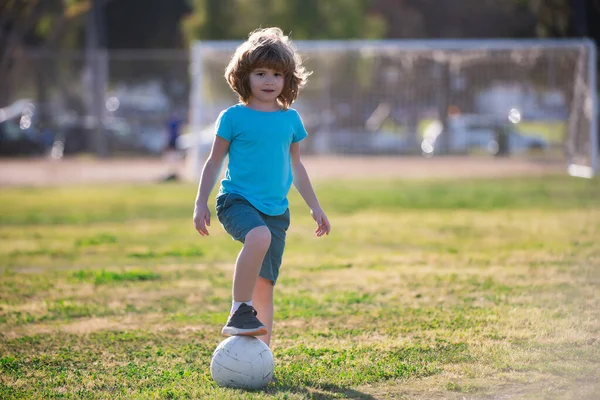 Soccer kids, child boy play football outdoor. Young boy with soccer ball doing kick. Football soccer players in motion. Cute boy in sport action. Boy kicking football on the field. — Zdjęcie stockowe