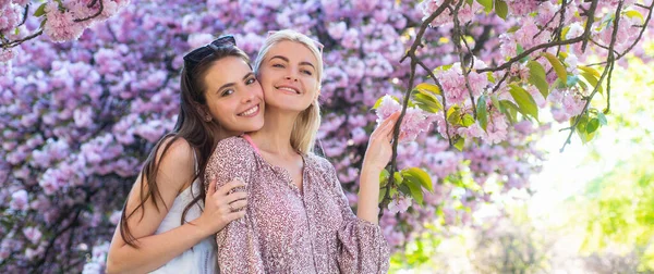 Banner de primavera com mulheres namoradas ao ar livre. Duas jovens mulheres relaxando em flores sakura. Meninas da primavera. — Fotografia de Stock