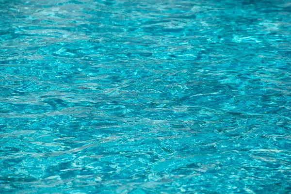 Fondo de agua azul en la piscina con reflejo solar, ondulación de la ola de agua en la piscina. Fondo de agua clara. — Foto de Stock