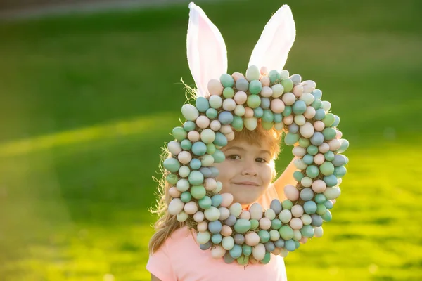Paskalya yumurtası ve tavşan kulaklı çocuk. Parkta mutlu bir Paskalya geçiren sevimli bir çocuk. Komik çocukların yüzü yakın plan.. — Stok fotoğraf