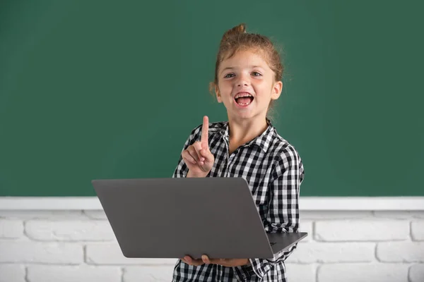 School child girl using digital pc laptop in class. Portrait of funny pupil of primary school study programming. — Foto Stock