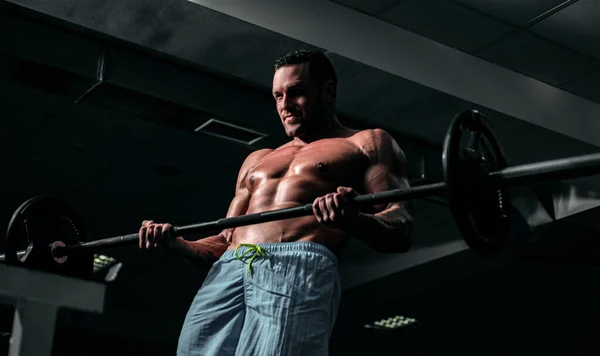 Halter kaldıran formda bir adam. Spor salonunda egzersiz yapan kaslı bir adam. Güçlü erkek, çıplak karın kasları.. — Stok fotoğraf