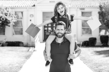 Baba ve oğul sırtına binip okuldan dönüyorlar. Okul, aile, eğitim ve açık hava konsepti.