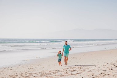Baba ve oğul yaz plajında koşuyor. Çocukluk ve ebeveynlik kavramı.