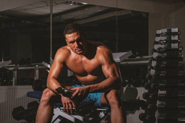 Spor salonunda su içen bir adam. Sağlıklı spor yaşam tarzı. Sporcu antrenmandan sonra dinleniyor..