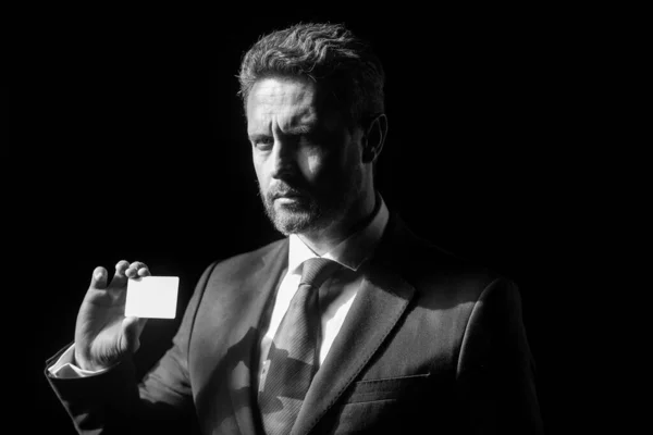 Primer plano retrato de exitoso hombre de negocios de mediana edad con tarjeta de crédito en traje sobre fondo negro. Hombre de negocios con cara segura. — Foto de Stock