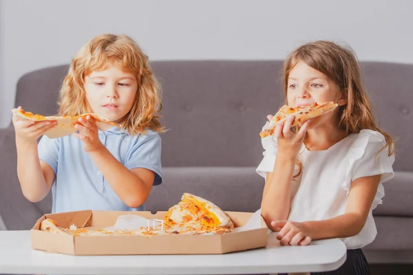 Children eating pizza. Little children friends, boy and girl bite pizza. — Stock Photo, Image