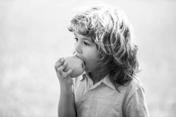 可爱的小男孩在户外吃苹果. — 图库照片
