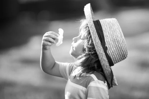 Caucasian child portrait close up. Kids in straw hat smelling plumeria flower on summer nature park. — Stock Fotó