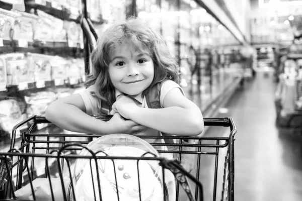 Улыбающийся ребенок с корзиной в продуктовом магазине или супермаркете. — стоковое фото