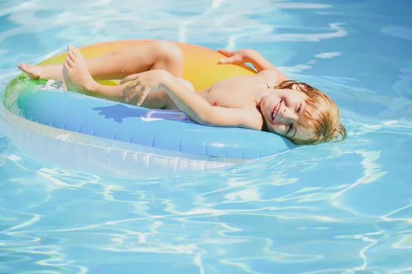 Bambino in piscina che gioca in acqua. Vacanze e viaggi con bambini. I bambini giocano all'aperto in estate. Ragazzo con anello galleggiante. — Foto Stock