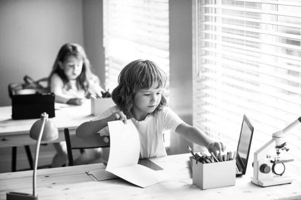 1年生。レッスンを書いている学校の少年。学校に戻る。机の上に笑顔の生徒が描いている。教室の小学校からの子供. — ストック写真