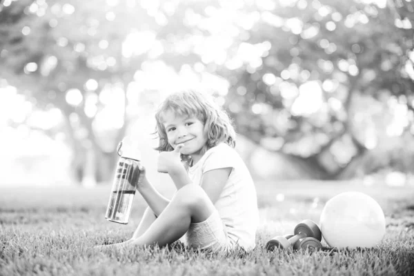 Sportos fiú vizet iszik a parkban. Gyerek Sport koncepció. Gyermek Fitness, egészség és energia, gyakorlatok súlyzókkal. Egészséges életmód kisgyermekek számára. — Stock Fotó