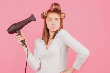 Saç kurutma makinesi ve bigudileri olan komik bir kadın. Saç kurutma makinesi olan kadın. Güzel bir kız, düz saçlı, saçlarını kurutan, profesyonel saç kurutma makinesi olan..