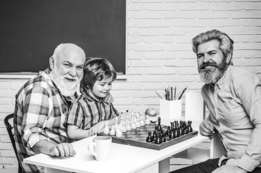 Baba oğluna satranç oynamayı öğretiyor. Büyükbabam torunu eğitti. Büyükbaba ve torun kavramı.