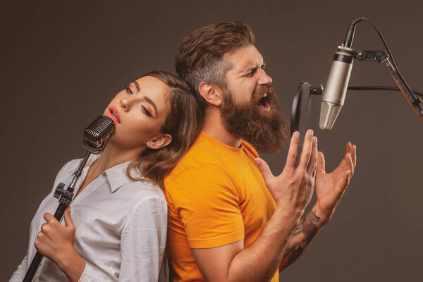Singer couple singing rock. Sound producer recording song in a music studio. Excited duet Karaoke.