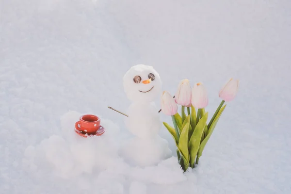 Helló tavasz, viszlát tél. Hóember kávéscsészével. Hóember virágokkal. — Stock Fotó