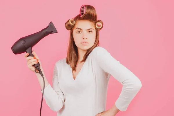 Young funny woman with hair dryer and rollers. Woman with hair dryer. Beautiful girl with straight hair drying hair with professional hairdryer. — Stock Photo, Image