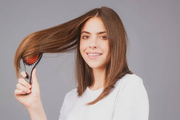 Aantrekkelijke glimlachende vrouw die haar kamt. Mooi meisje met haarkam kamt haar. Begrip haarverzorging. — Stockfoto