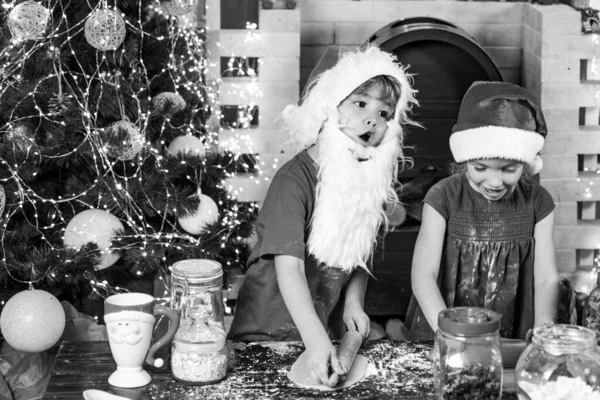 Weihnachtsfamilie. Frohes neues Jahr. Lustige Kinderköche mit Weihnachtsmützen bereiten Festtagsessen zu. Lustige Kinder bereiten den Teig in der Küche mit Mehl zu. — Stockfoto