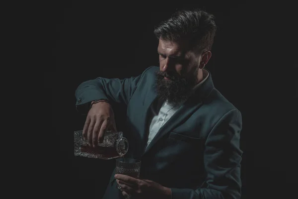 Hipster com barba e bigode no terno bebe álcool após o dia de trabalho. Sommelier saboreia bebida alcoólica cara . — Fotografia de Stock