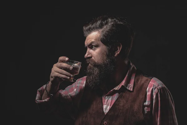 Um homem elegante que sofre de alcoolismo bebendo uísque. Homem barbudo e bonito a segurar um copo de uísque. Homem atraente no bar de uísque. — Fotografia de Stock