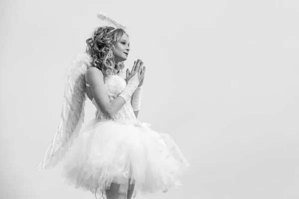 Pray. A beautiful teen with blonde curly hair as cupid - Valentines Day. Valentine. Valentines day pray cupid. Girl dressed as an angel on a light heaven background. — ストック写真