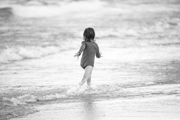 Blonder Junge läuft und amüsiert sich am Strand am blauen Meer im Sommer. — Stockfoto