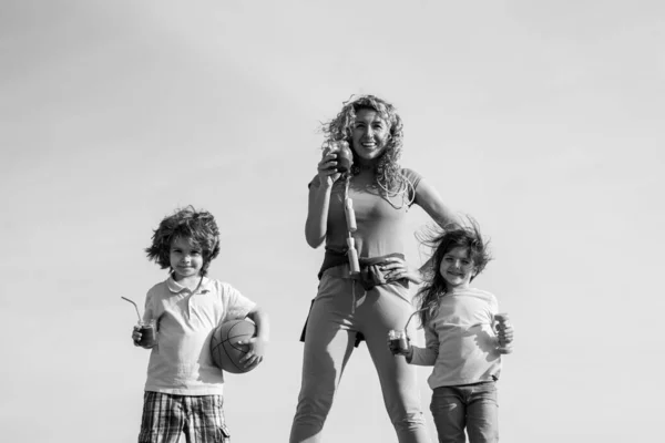 Stile di vita sano per famiglie sportive. Famiglia felice Madre e bambino in piedi su sfondo cielo. Madre, figlia e figlio microfonare sport . — Foto Stock