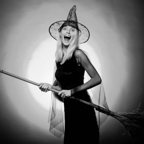 Surprised woman on witches hat and costume with broom. Vampire Halloween Woman portrait. Emotional young women on halloween party over red background. Looking camera. — Stock Photo, Image