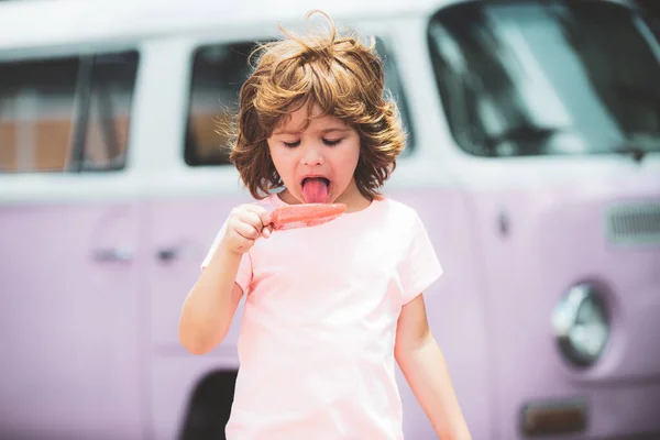 Παγωτατζή. Funy σγουρά παιδί με icecream εξωτερική. Αγοράκι με ροζ φόρεμα να τρώει παγωτό.. — Φωτογραφία Αρχείου