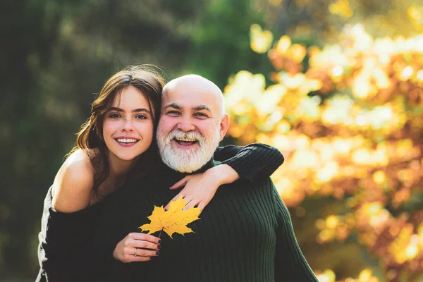 Портрет счастливой молодой женщины, обнимающей дедушку в осеннем парке. — стоковое фото