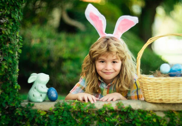 Portret van konijnenjongen op Paasdag. Kind jongen jagen eieren in de tuin, lente familie vakantie. Paashaas kinderen jagen op paaseieren. Grappig kind gezicht dragen konijnenoren. — Stockfoto