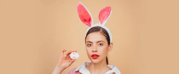 Pasen spandoek met konijnenvrouw. Lipstick kus afdruk op paasei. Paashaas, konijn en meisje. Portret van een gelukkige vrouw in konijnenoren. Eierenjacht. — Stockfoto