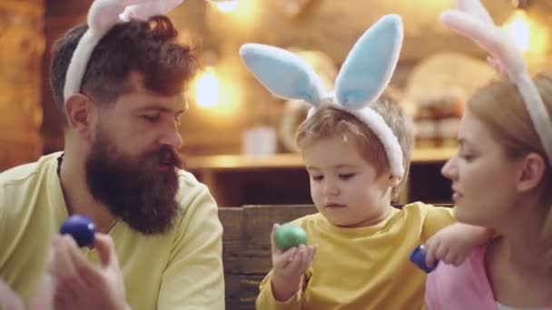 Happy family painted Easter eggs, wearing bunny ears on Easter day. — Stock videók
