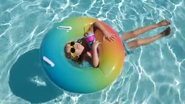 Niño feliz jugando con colorido anillo de natación en la piscina en el día de verano. Juguetes de agua infantil. Los niños juegan en el resort tropical. Vacaciones familiares en playa. — Vídeos de Stock