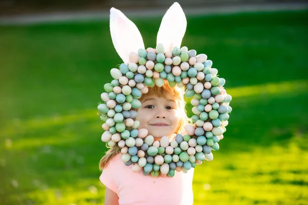 Niño de Pascua en orejas de conejo cazando huevos de Pascua al aire libre. Lindo niño en traje de conejo con orejas de conejo divertirse en el parque. — Foto de Stock