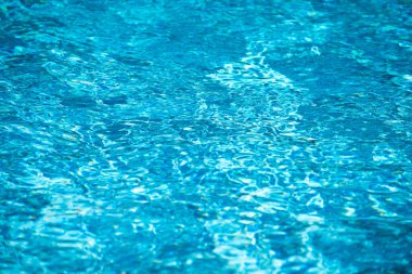 Yüzme havuzundaki mavi suyun arka planında güneş yansıması, havuzda dalgalı su dalgaları. Temiz su arkaplanı.