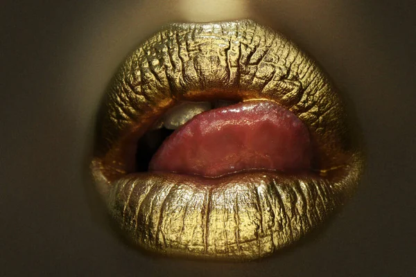 Sexy jazyk. Smyslné lízání. Zlaté rty. Zlatá barva z úst. Zlaté rty na ženských ústech s make-upem. Smyslný a kreativní design pro zlatý kov. — Stock fotografie