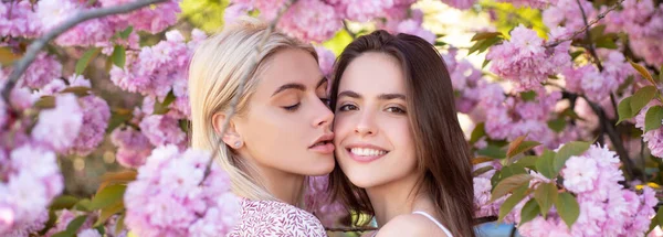 Spring banner with women girlfriends outdoor. Spring girls. Lesbian couple kissing. Beautiful spring sexy young woman with sakura flowers. Sensual kiss. Lgbt. — Fotografia de Stock